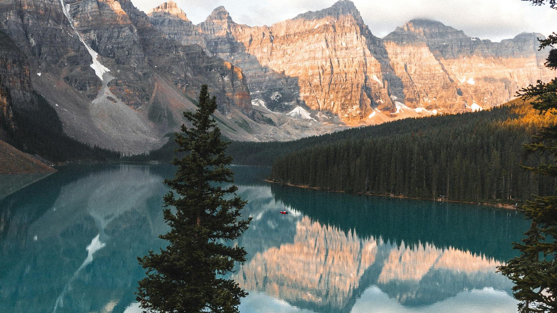Moraine Lake at sunrise, glacier-fed turquoise water ringed by the Valley of the Ten Peaks