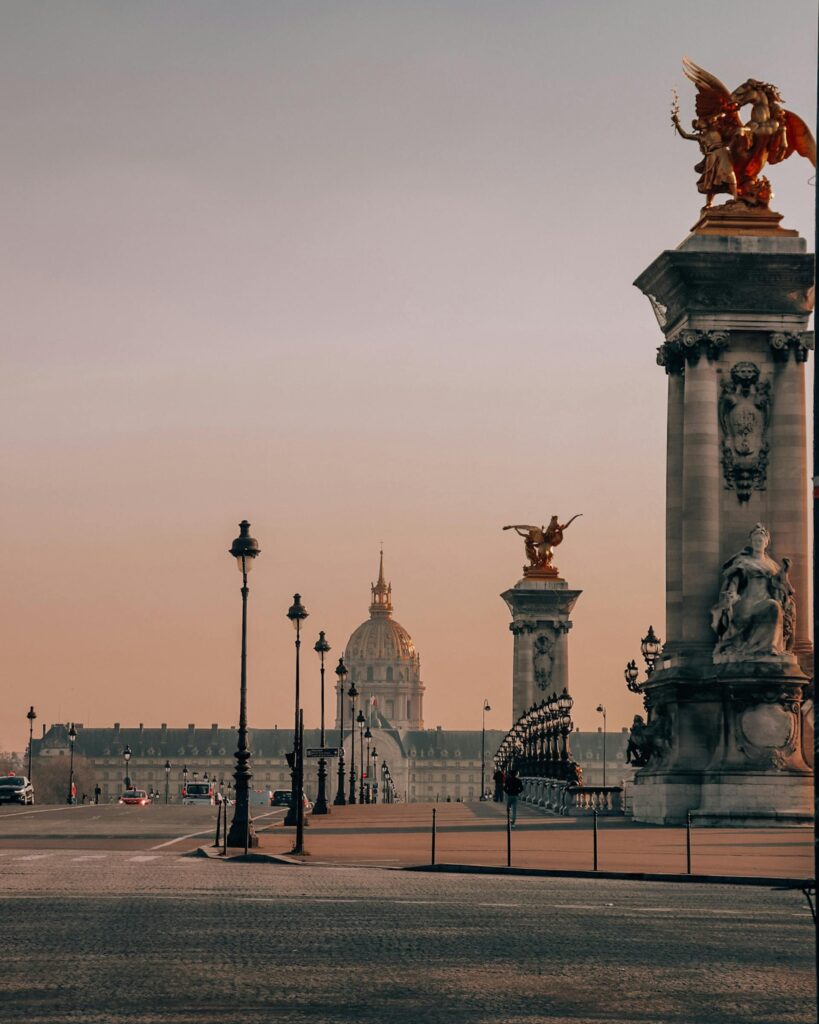Pont Alexandre III gilded sculptures with the Hôtel des Invalides dome at sunset, Paris, France