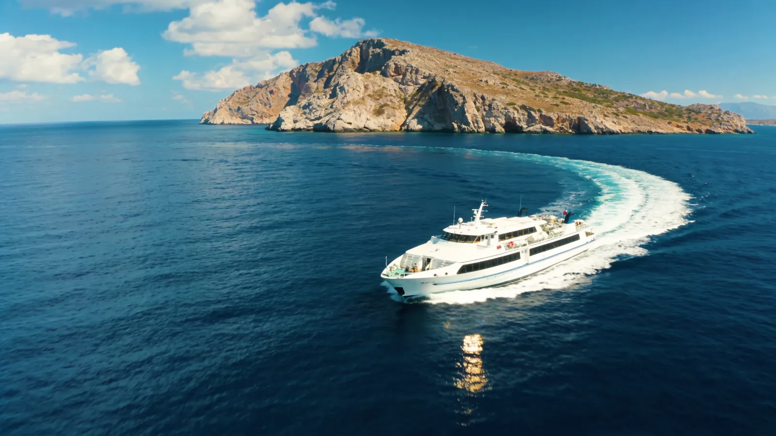 Ferry crossing deep blue water towards a Greek island
