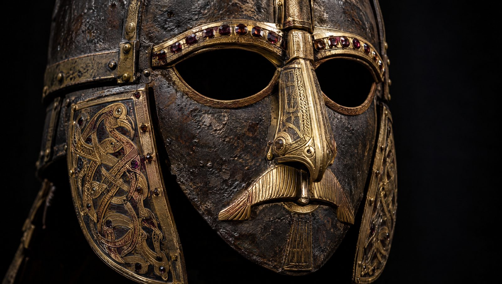 Close-up of an Anglo-Saxon iron helmet face mask with gilt-bronze eyebrows inlaid with garnets and animal ornament on the cheek guards