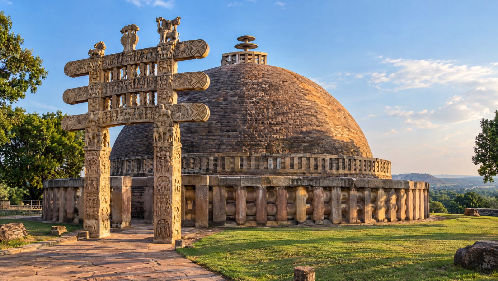 The Great Stupa at Sanchi with its hemispherical dome, stone railing and a carved gateway in late-afternoon light